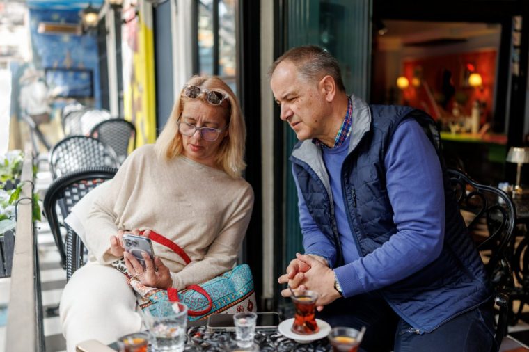 Relaxed mature couple using smart phone in sidewalk caf??