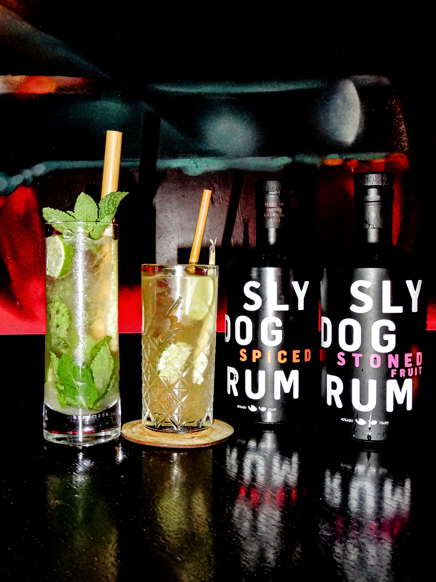 two cocktails presented next to two bottles of rum