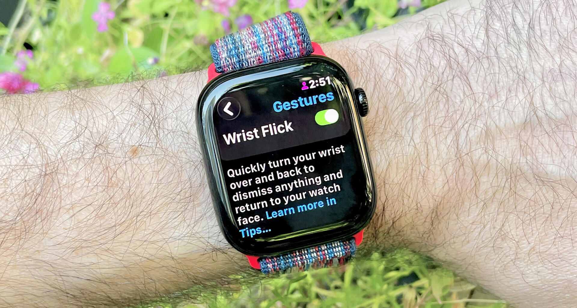 Close-up of an Apple Watch 10 on a user's wrist showing the menu option to turn on the new Wrist Flick gesture in watchOS 26