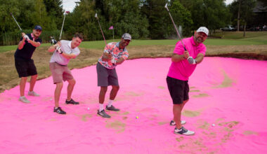 four golfers hitting from pink sand at a charity golf day