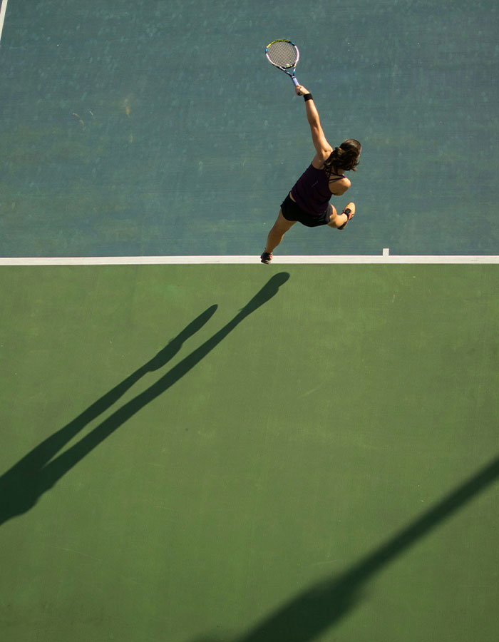 Tennis pro in action hitting a serve on court, highlighting the sports career of a young female athlete.