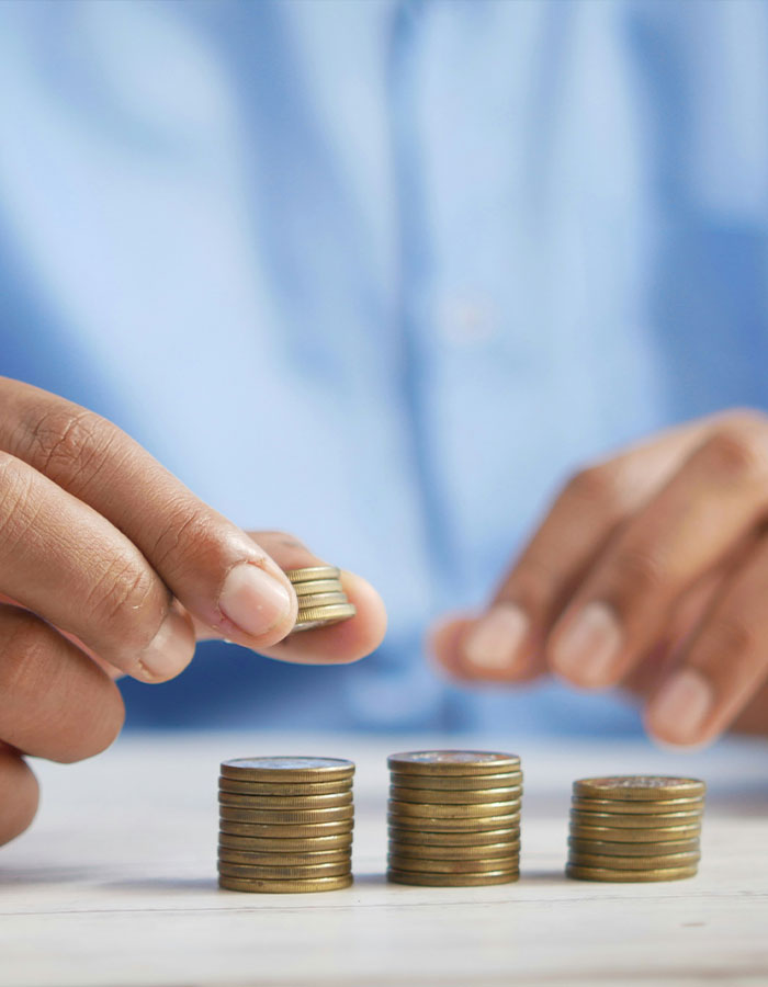 Close-up of a person stacking coins representing financial control and male ego in money management.