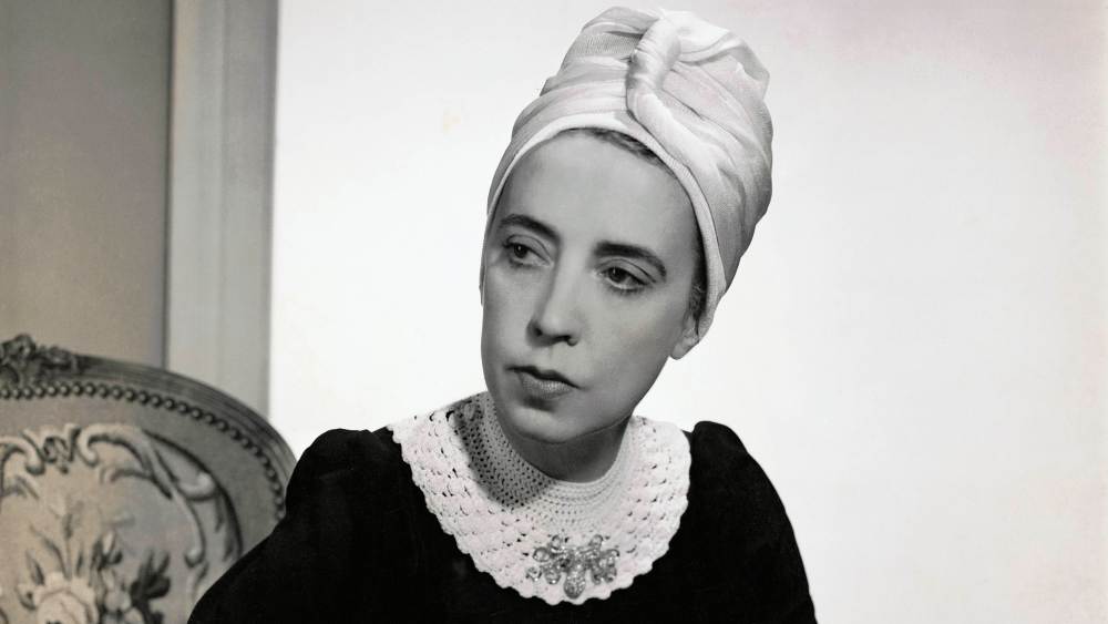 Designer Elsa Schiaparelli wearing black silk dress with crocheted collar of her own design and a tuban. (Photo by Fredrich Baker/Condé Nast via Getty Images)