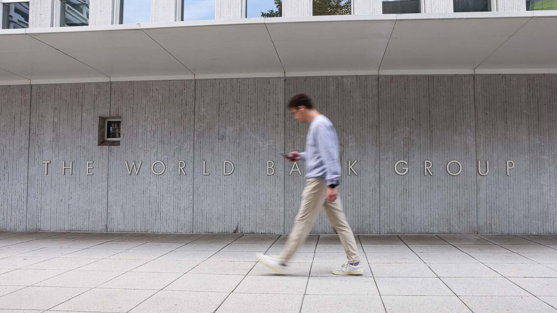 Man walks past concrete wall with sign that reads World Bank Group