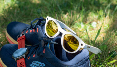 A pair of warm white limited edition Oakley Meta HSTN smart glasses with PRIZM lenses with running shoes and an Amazfit Balance 2 smartwatch