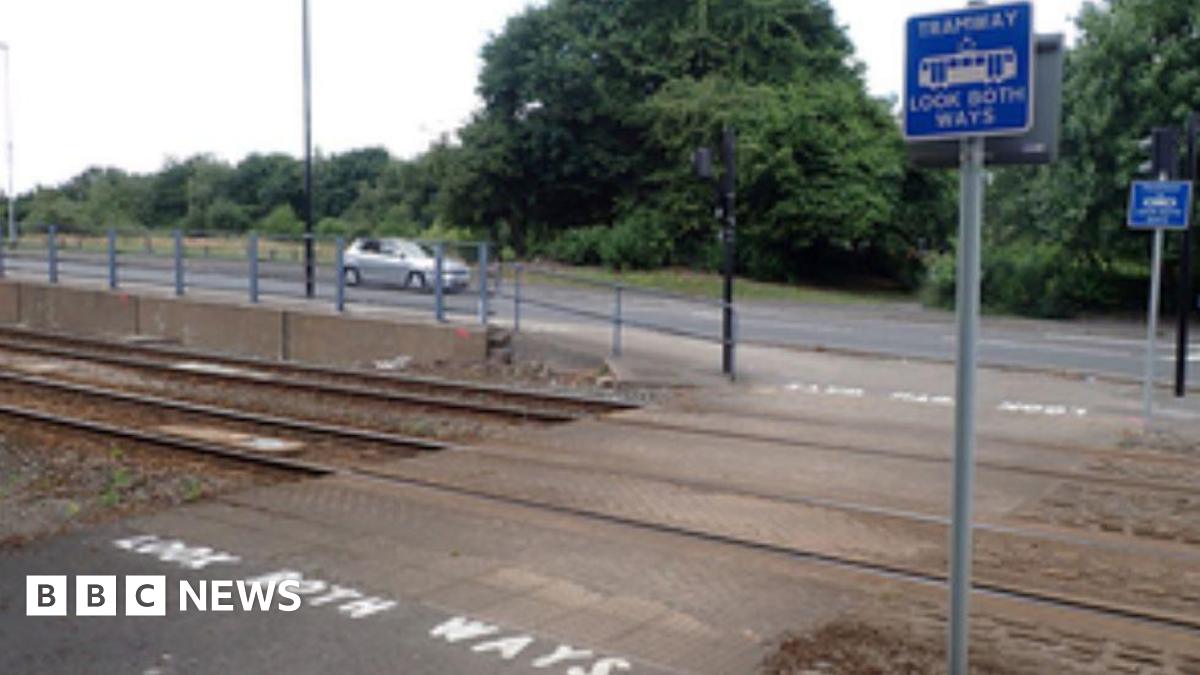 A crossing on a tramway. There are two poles with blue signs reading 'Tramway look both ways' and white paint on the road which says 'Look both ways'.