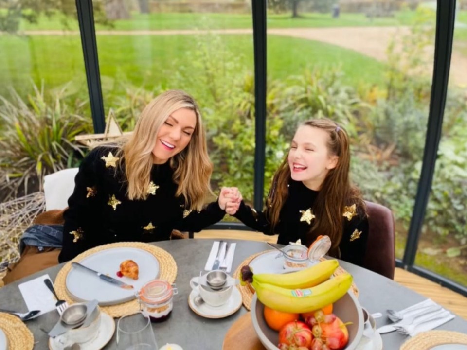 A mother and daughter hold hands at a breakfast table.