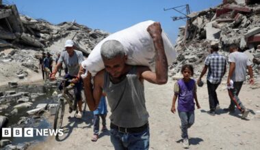 A Palestinian man carries a bag with aid supplies that entered Gaza, in Beit Lahia, northern Gaza (27 July 2025)