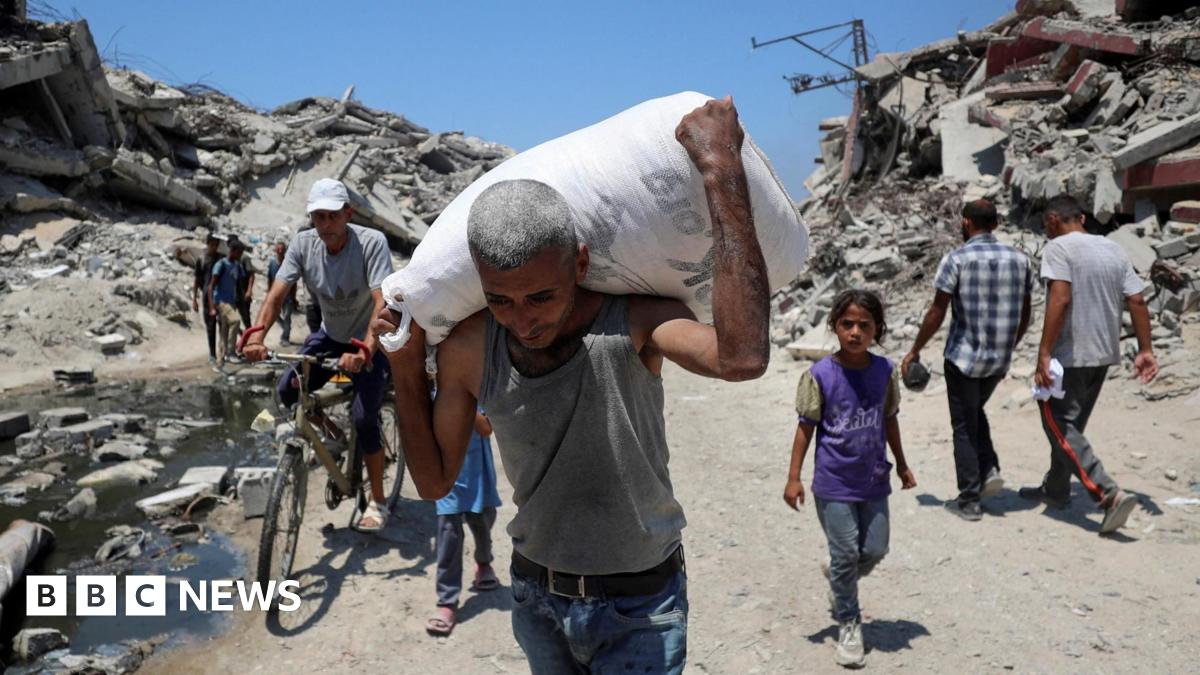 A Palestinian man carries a bag with aid supplies that entered Gaza, in Beit Lahia, northern Gaza (27 July 2025)