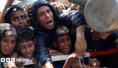 Palestinians react as they wait to receive food from a charity kitchen