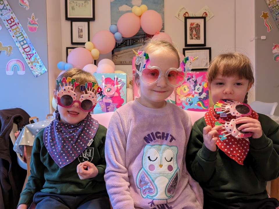 Three young girls wearing birthday-themed glasses.