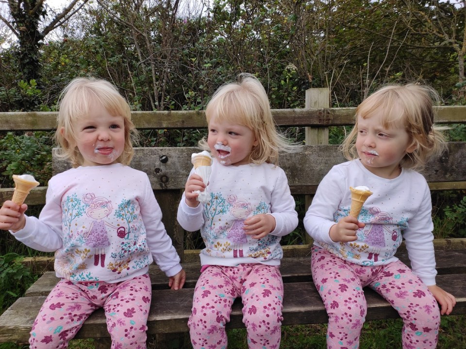 Triplet girls eating ice cream cones.
