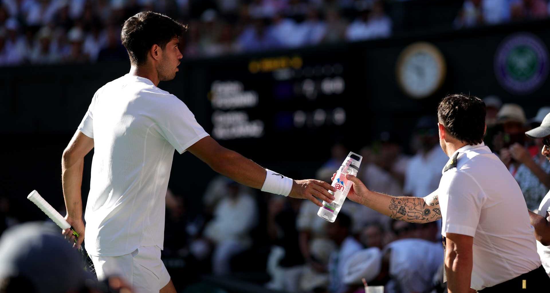 Carlos Alcaraz passes water for a fan amid record-breaking heat at Wimbledon on Monday.