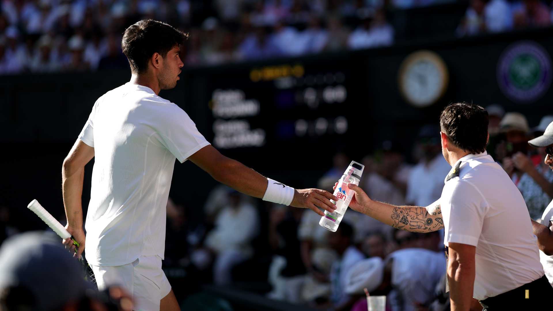Carlos Alcaraz passes water for a fan amid record-breaking heat at Wimbledon on Monday. 