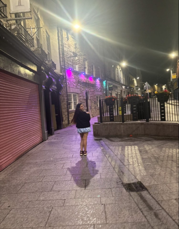Woman walking down a city street at night.
