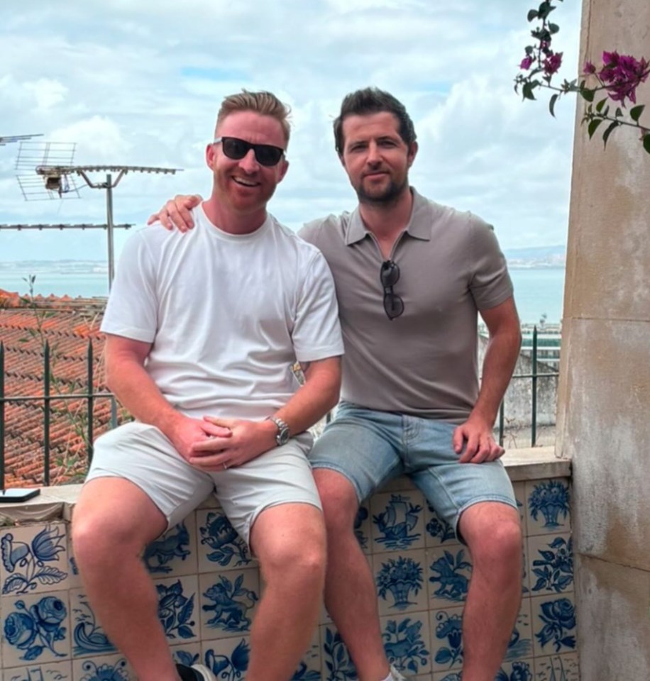 Two men sitting on a tiled wall, overlooking a cityscape.