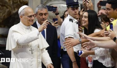 The pope waves to young worshipers in St Peter's as they film him on their mobile phones