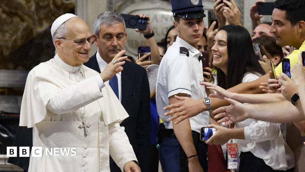 The pope waves to young worshipers in St Peter's as they film him on their mobile phones