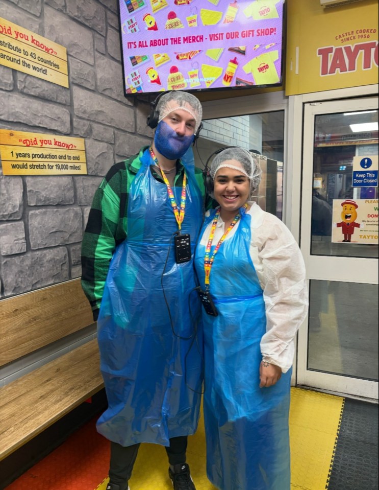 Two people wearing blue aprons and headsets in a Tayto crisps factory.