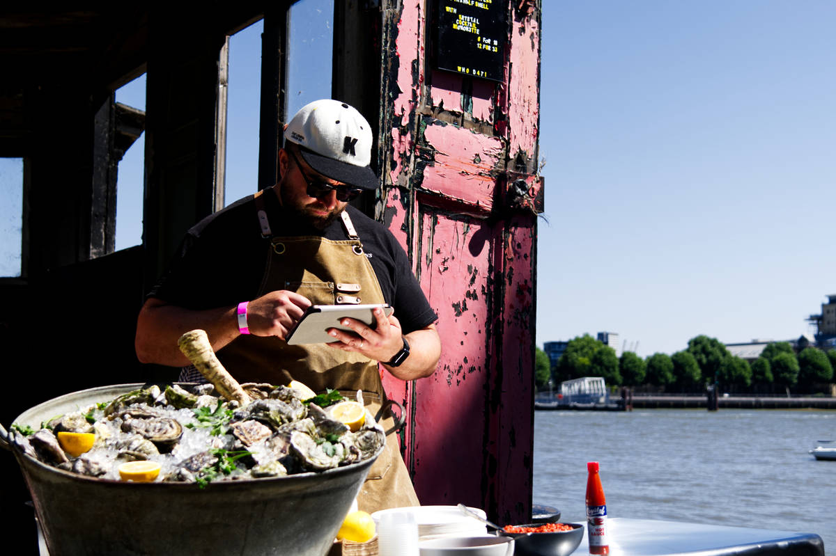 someone standing behind an impressive selection of oysters by the thames