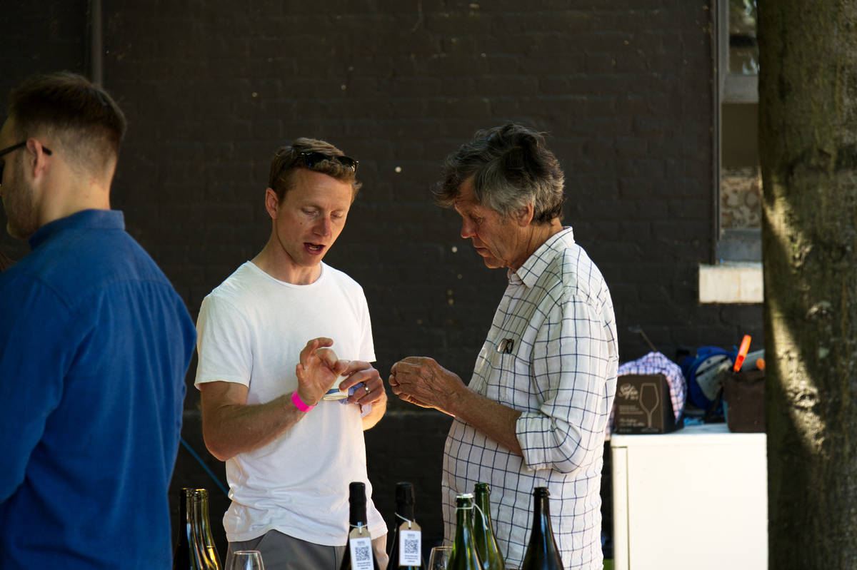 two people talking behind a selection of bottles of wine