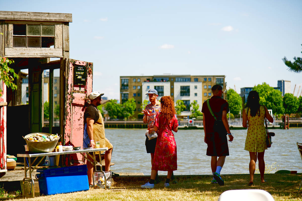 people standing by the thames in a small grassed area enjoying the view