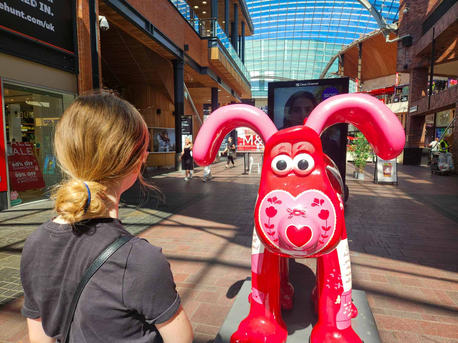 My daughter looks at a statue of Gromit decorated with hearts and flowers at Cabot Circus - my Gromit Unleashed 3 review of a visit to Bristol with kids