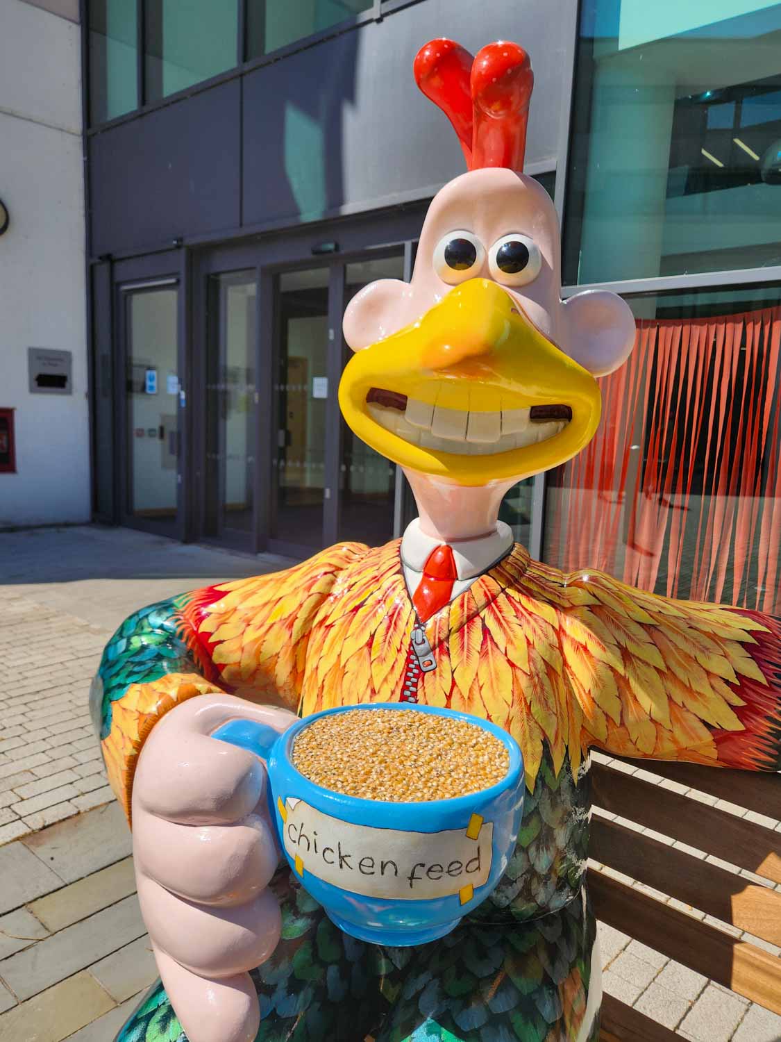 Statue of Wallace as a chicken, with a cup of chickenfeed - my Gromit Unleashed 3 review during a visit to Bristol with kids