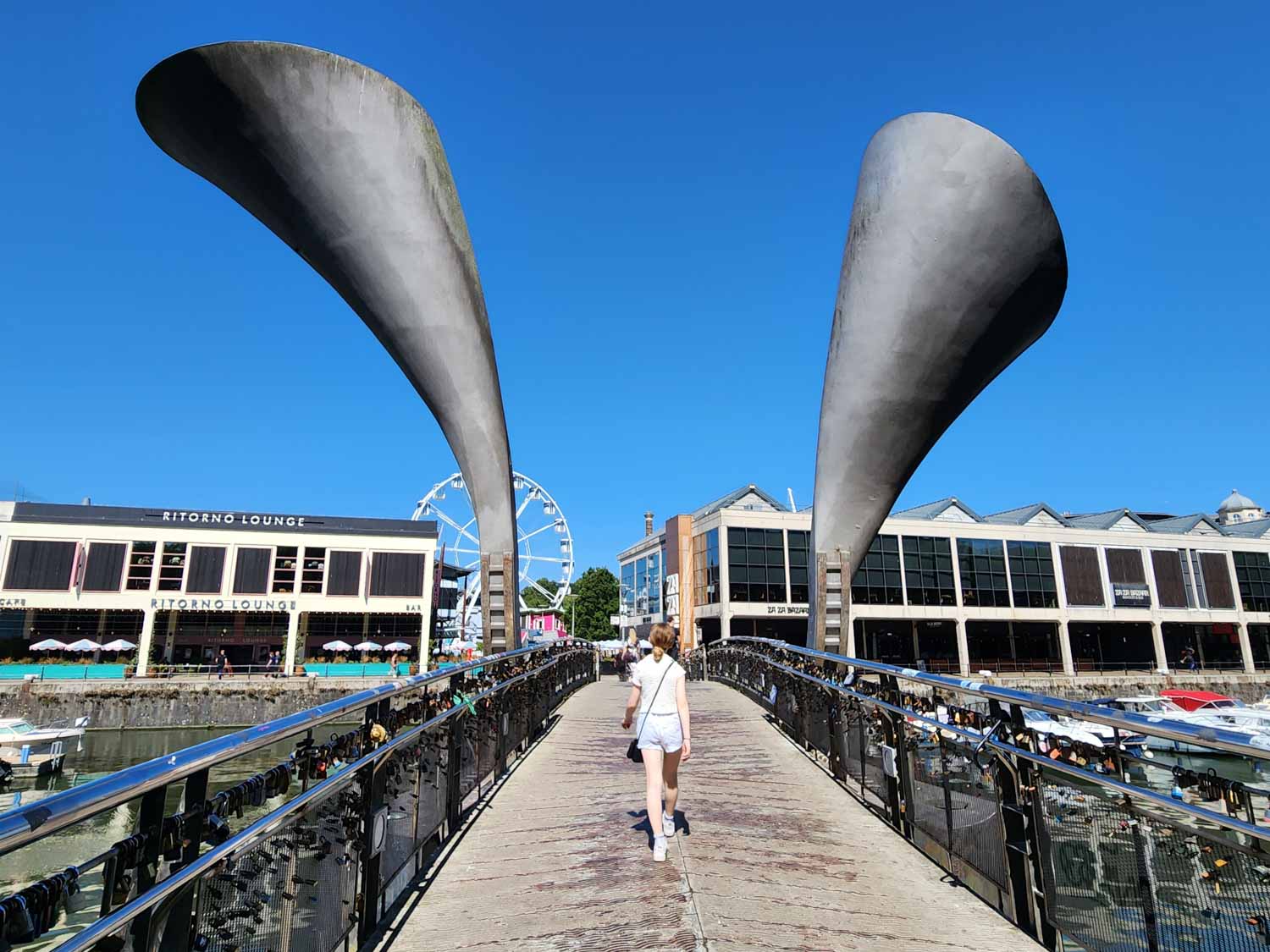 My daughter walks across the bridge over the Harbourfront towards We The Curious on a sunny day during a short break in Bristol with kids