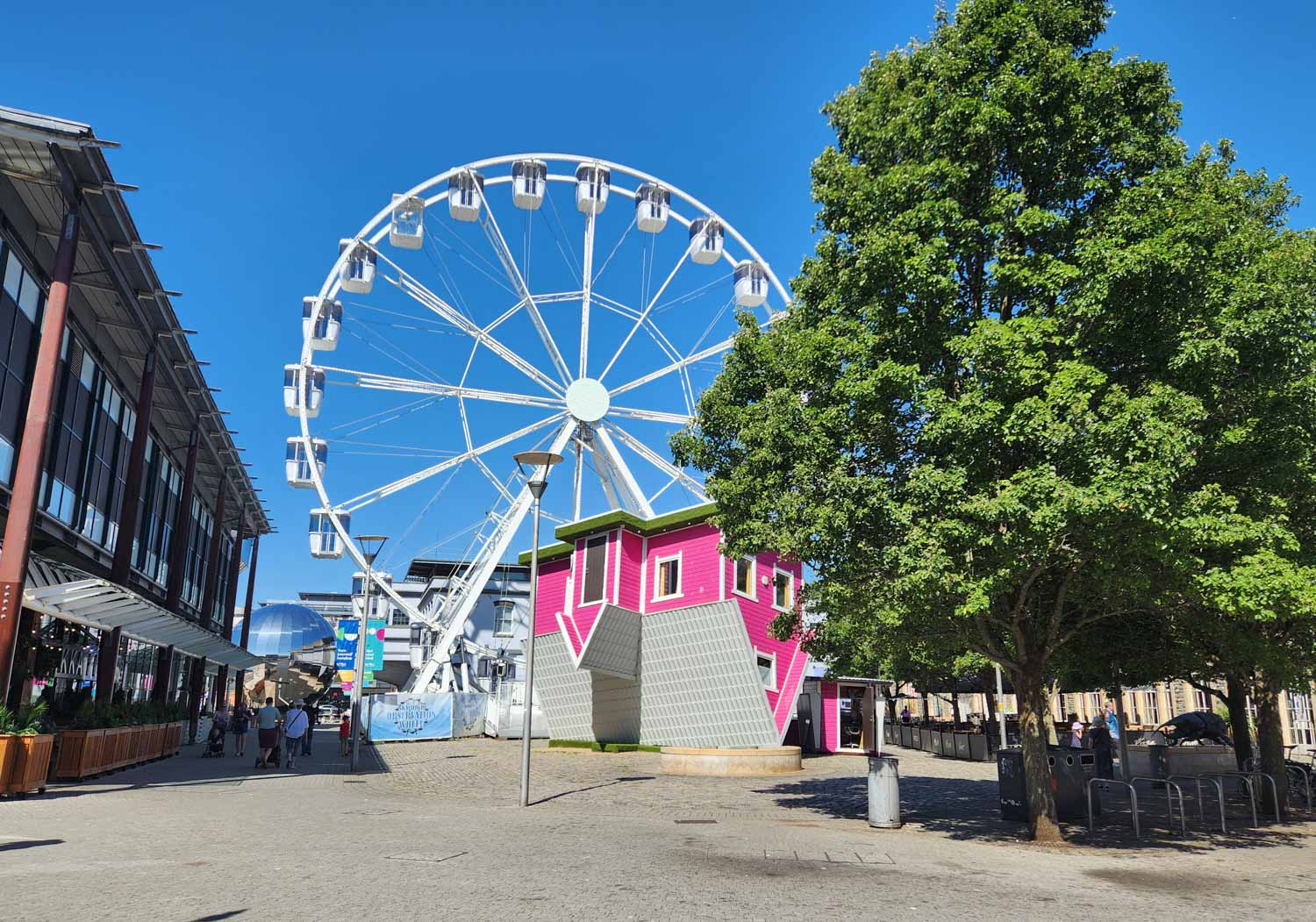 View of the pink upsidedown house, ferris wheel and We The Curious just seen behind, during a short break in Bristol with kids