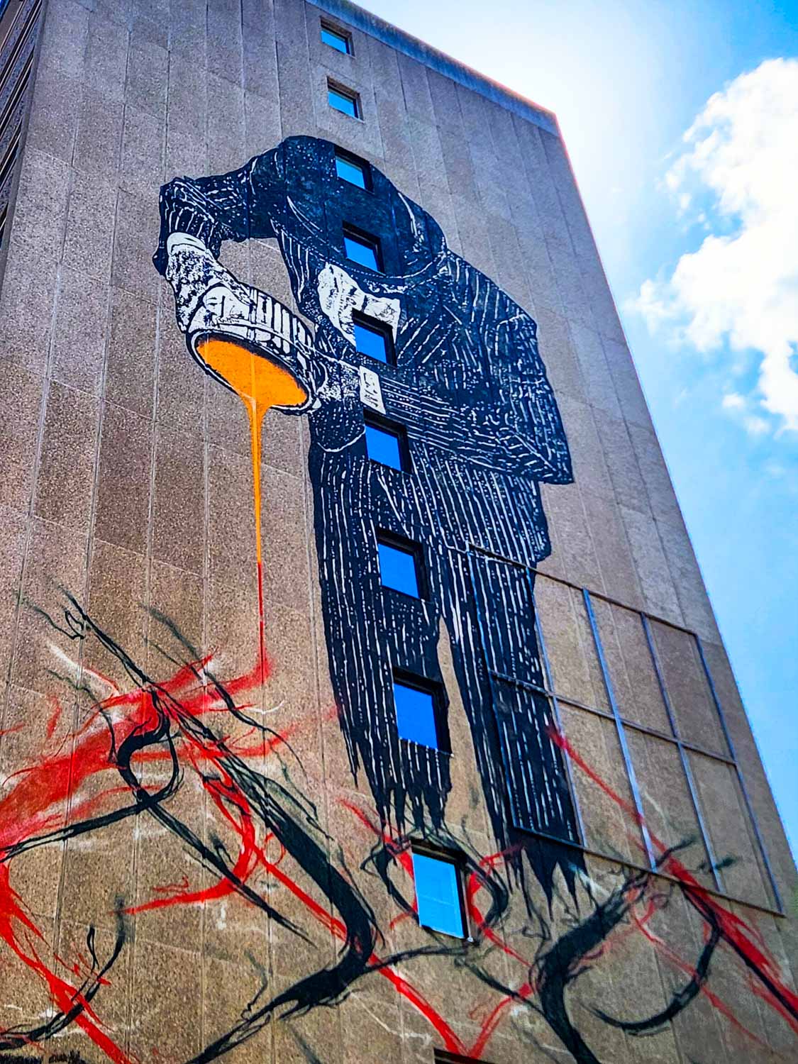 Street art in Bristol showing a banker pouring something flammable onto a fire - one of the sights from a walking tour of Bristol with kids