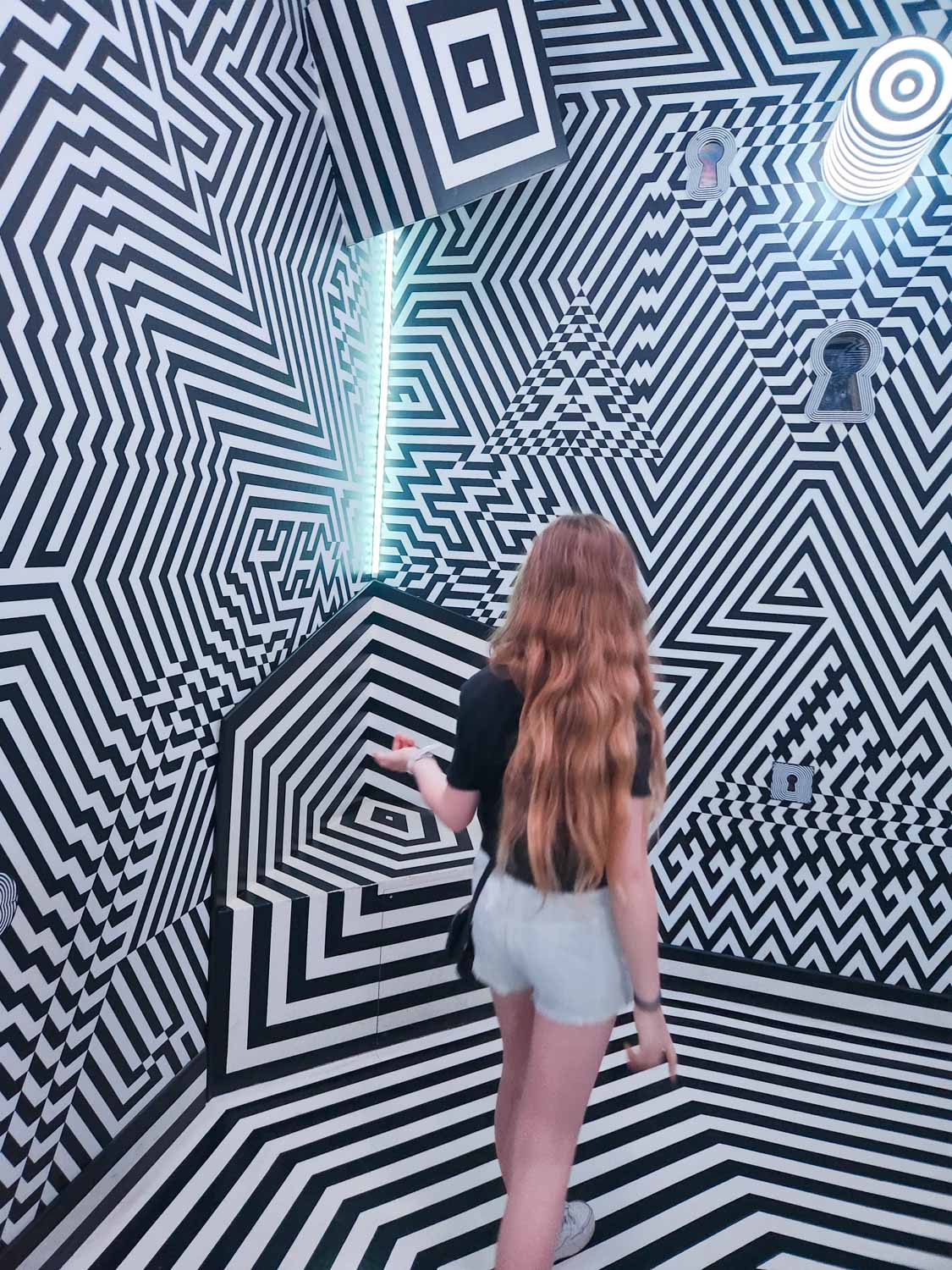 My daughter walks into a room patterned in black and white lines to trick the eyes at Wake The Tiger - one of the most unusual things to do in Bristol with kids