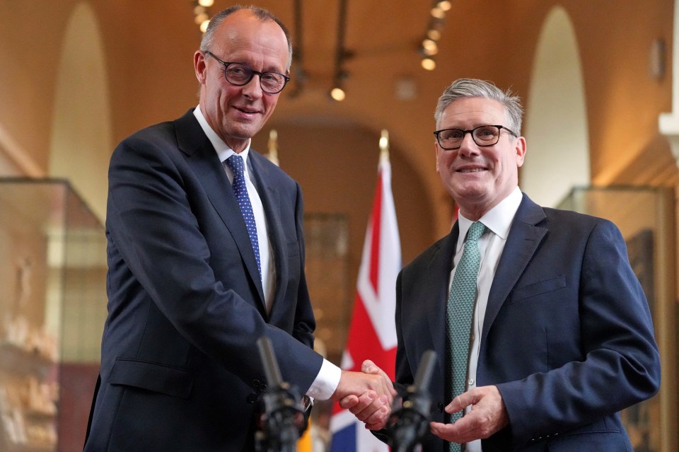 Keir Starmer and Friedrich Merz shaking hands at a treaty signing ceremony.