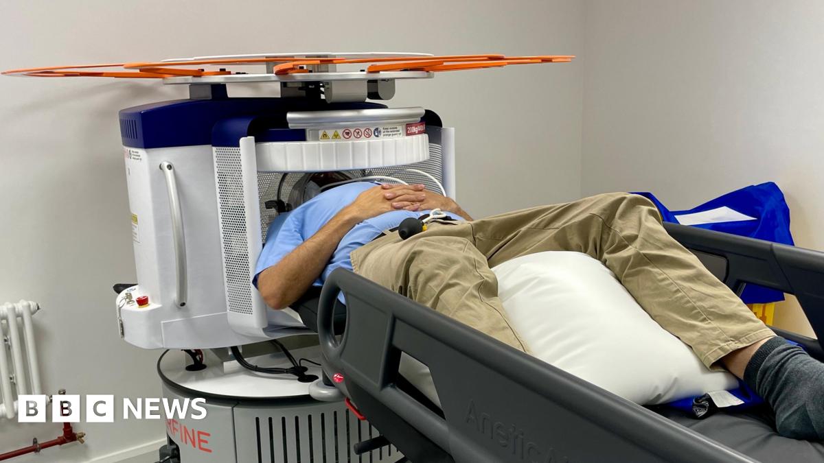 A man lying on his back on a medical trolley with his head inside a scanner