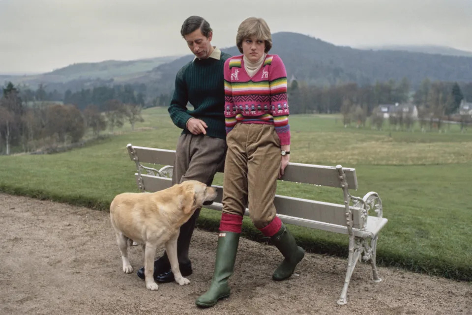 Princess Diana wearing a pink sweater and Prince Charles posing on a bench in Balmoral, Scotland