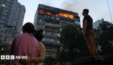 People look at burning apartments in a high-rise residential building hit by Russian shelling on July 10, 2025 in Kyiv, Ukraine.