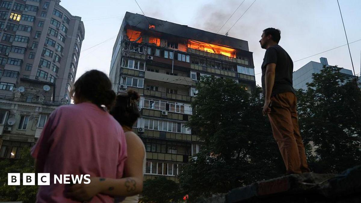 People look at burning apartments in a high-rise residential building hit by Russian shelling on July 10, 2025 in Kyiv, Ukraine.