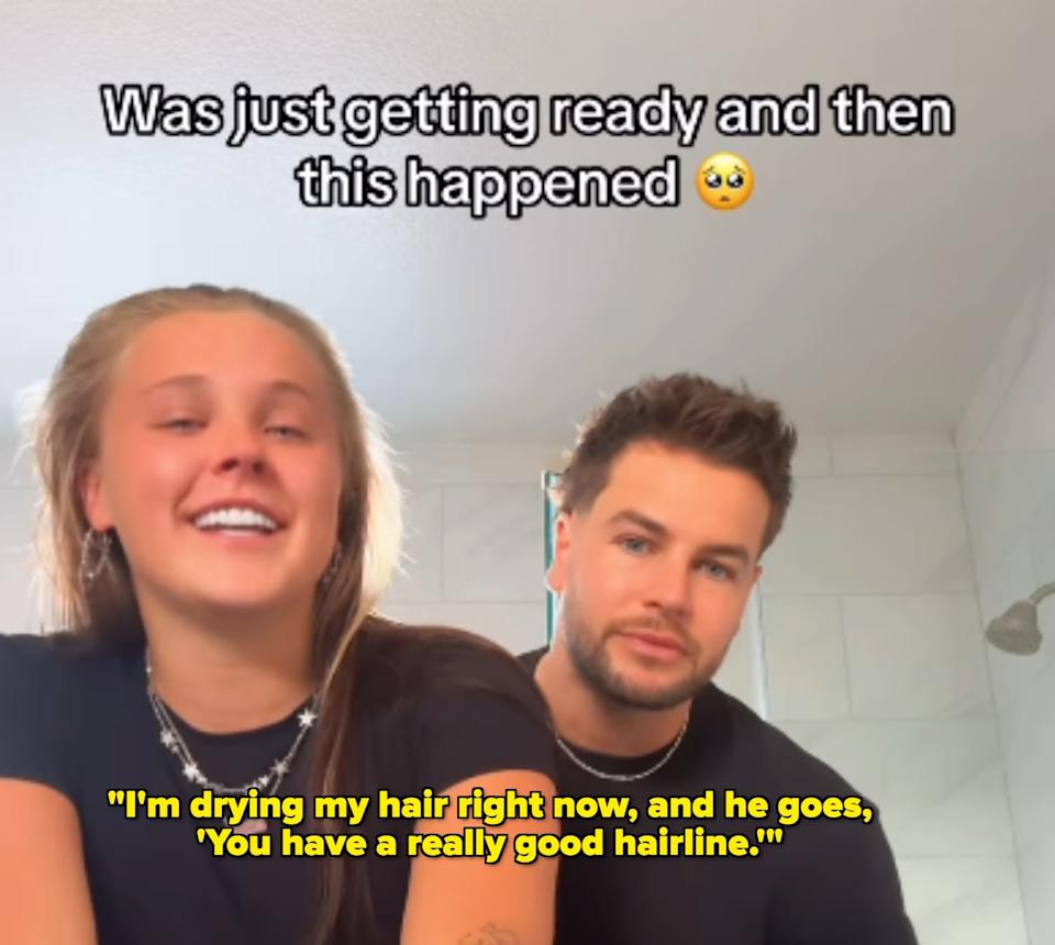 Two people smiling in a home setting. The person on the left is wearing a casual black top and white pants. Text above them reads: “Was just getting ready and then this happened ?”