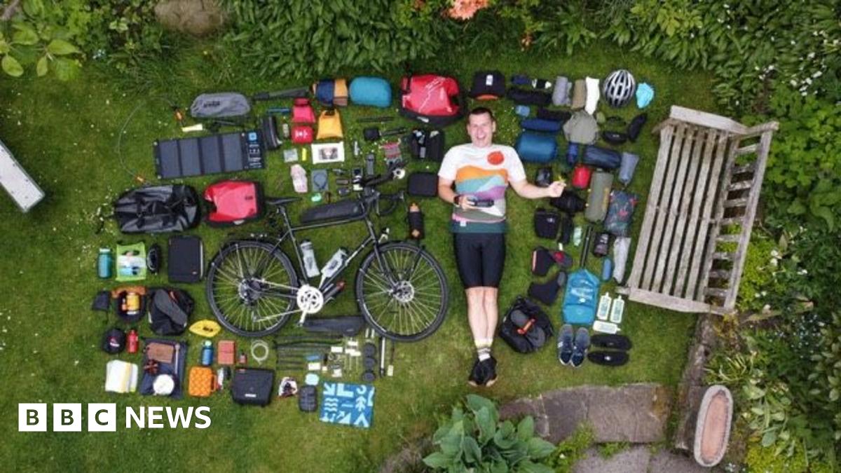 Simon Watts laying down in a garden surrounded by various items laid out next to his bike.
