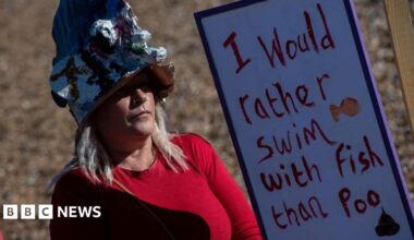 Campaigner against dumping sewage into the coast around Kent, stands with a sign which reads I would rather swim with fish than poo.