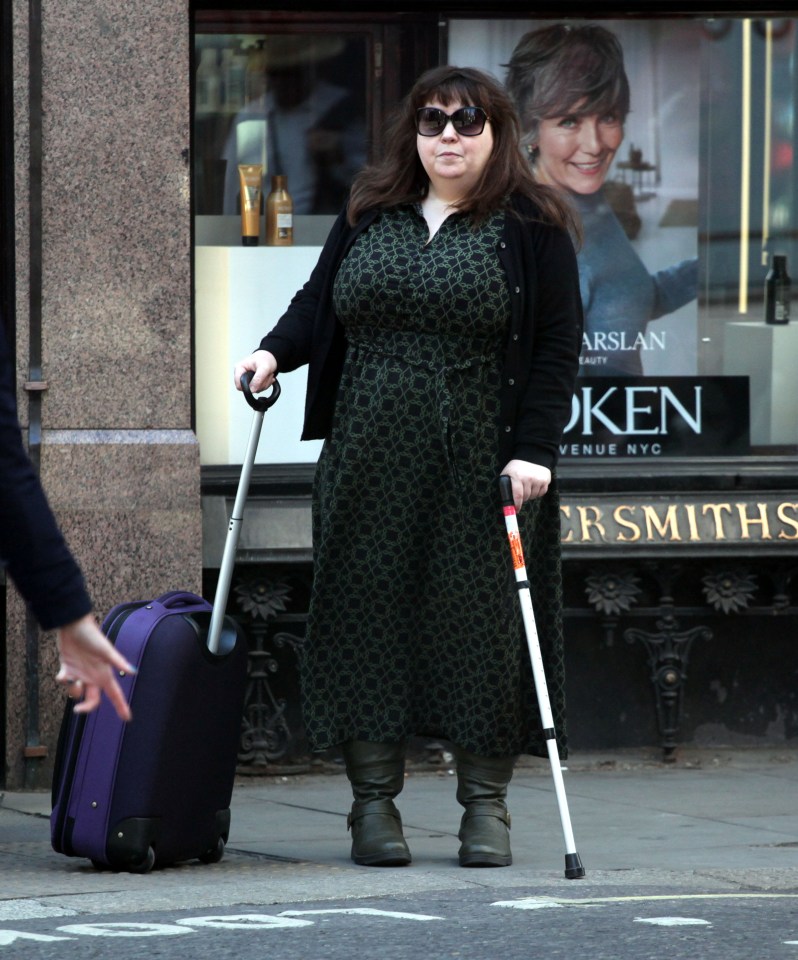 Woman with a cane and suitcase outside a London court.