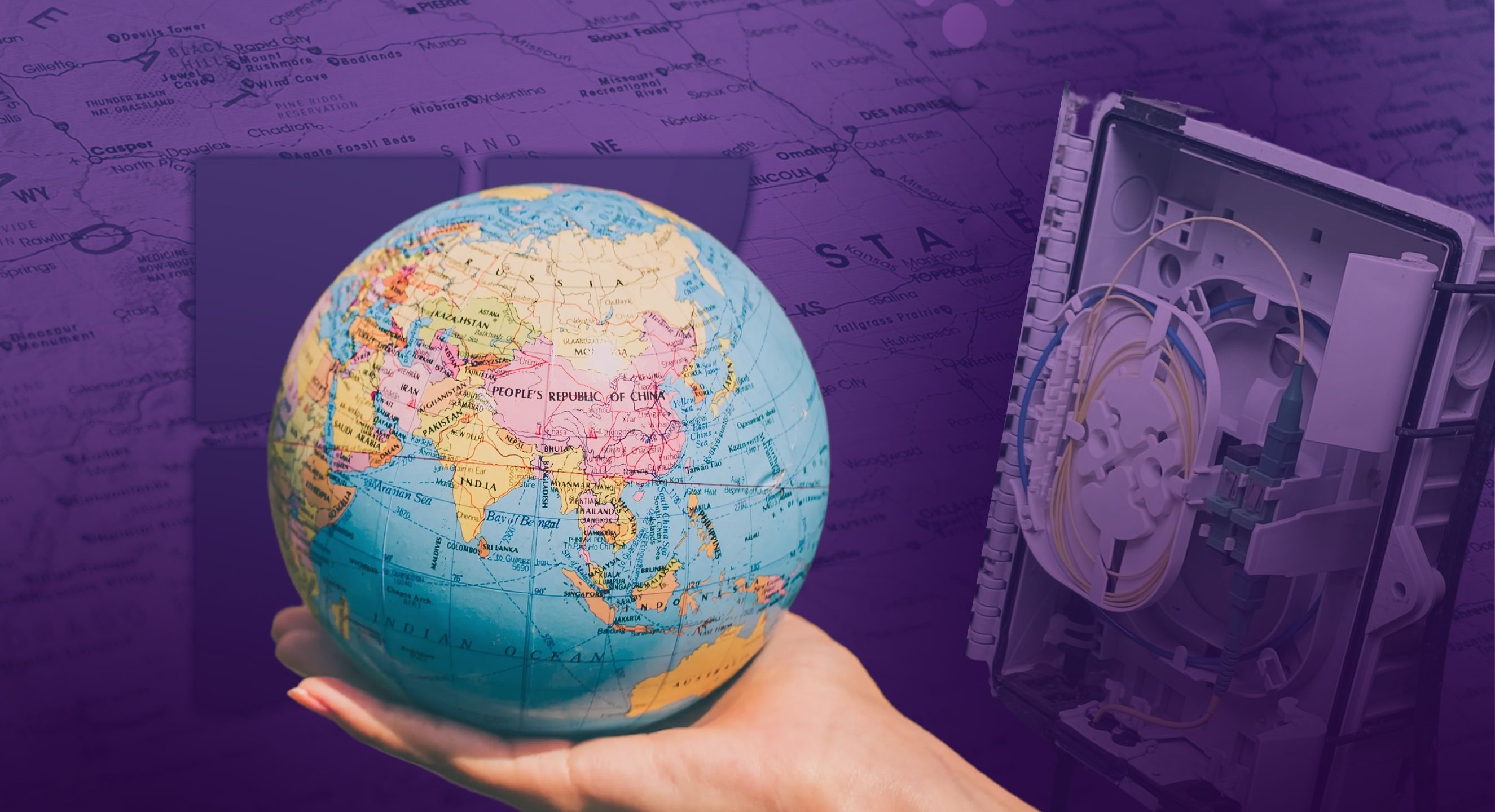 A hand holding a globe with a map and a fiber optic internet box
