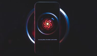 the ChatGPT logo sits on a phone with a dark background which is on top of a dark camera