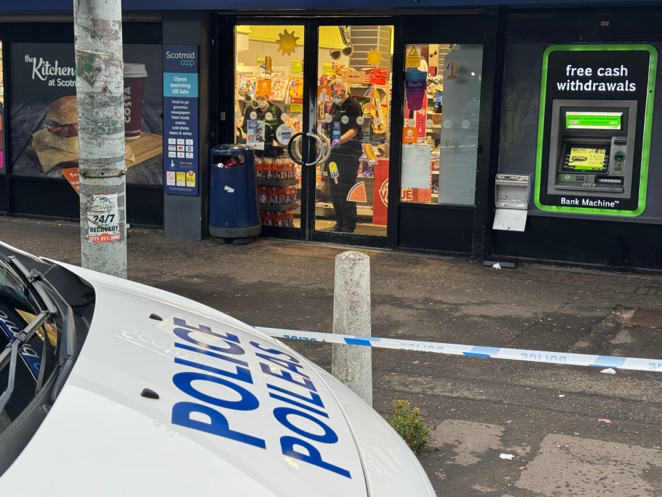 A Co-op store employee in Glasgow, behind a counter full of magazines and candy.