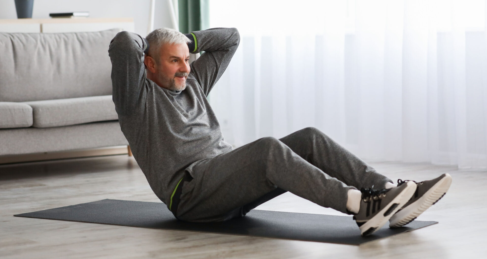 man on an exercise mat sitting up with his hands behind his head