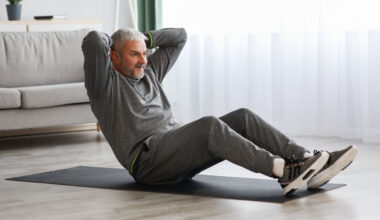man on an exercise mat sitting up with his hands behind his head