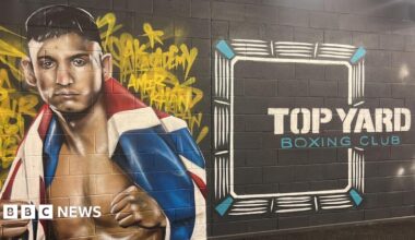 A mural is on a wall of the gym which has a picture of Amir Khan on the left with a United Kingdom flag around him. On the right of the mural it says 'Top Yard Boxing Club' in white and blue writing.