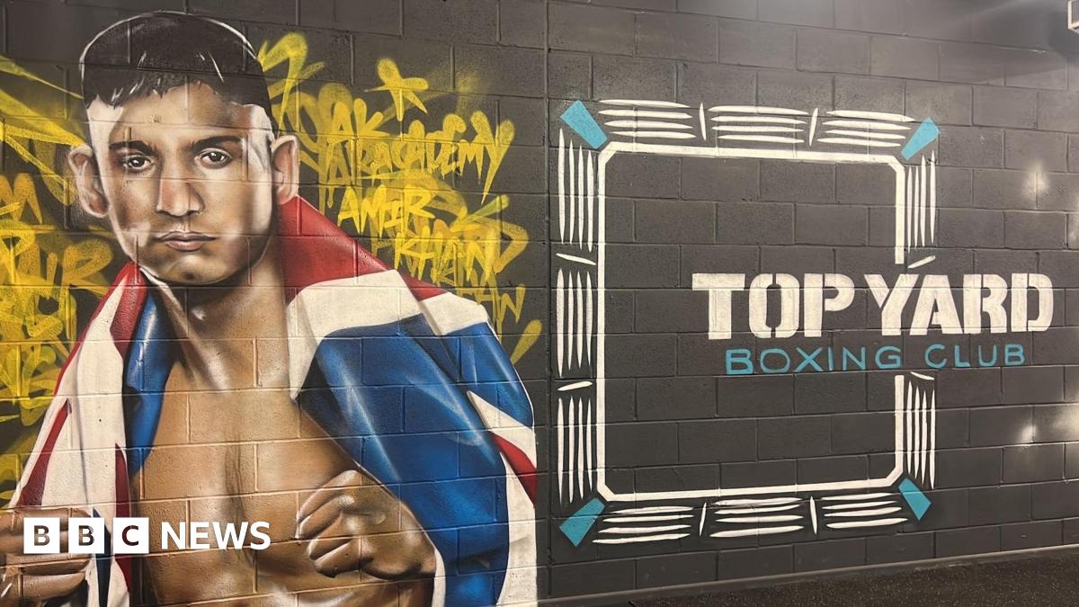 A mural is on a wall of the gym which has a picture of Amir Khan on the left with a United Kingdom flag around him. On the right of the mural it says 'Top Yard Boxing Club' in white and blue writing.