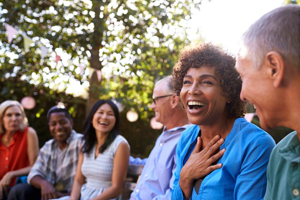 Group of mature friends socialising in a backyard together. (Getty Images)