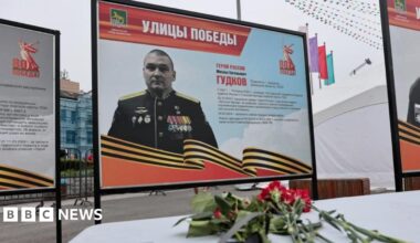 Flowers placed in front of a board with a photograph of Major General Mikhail Gudkov, the deputy head of the Russian Navy